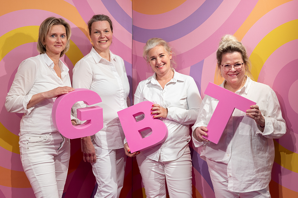 Het team van Mondhygiënepraktijk Prinsenland voor een roze achtergrond